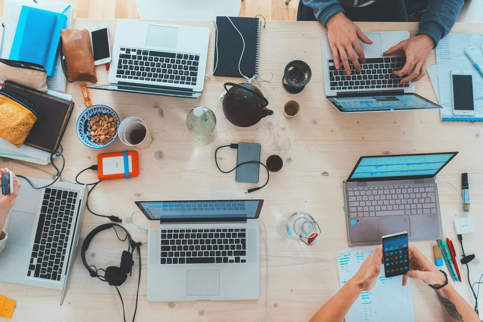 A shared workspace with laptops and people collaborating.
